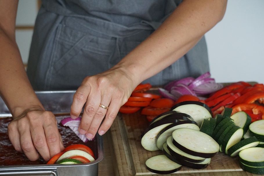 Monterar en god och vegetarisk Ratatouille i en rostfri ugnsform