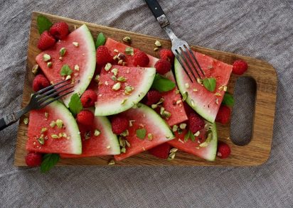 Vattenmelon, hallon, pistagenötter och mynta på en skärbräda
