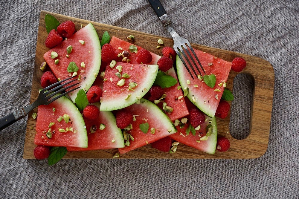 Vattenmelon, hallon, pistagenötter och mynta på en skärbräda