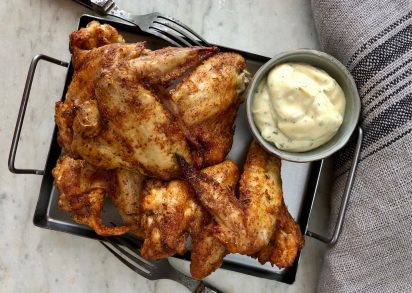 Ugnsstekta kycklingvingar på plåt, serverade med en vitlök och chilimajonnäs.