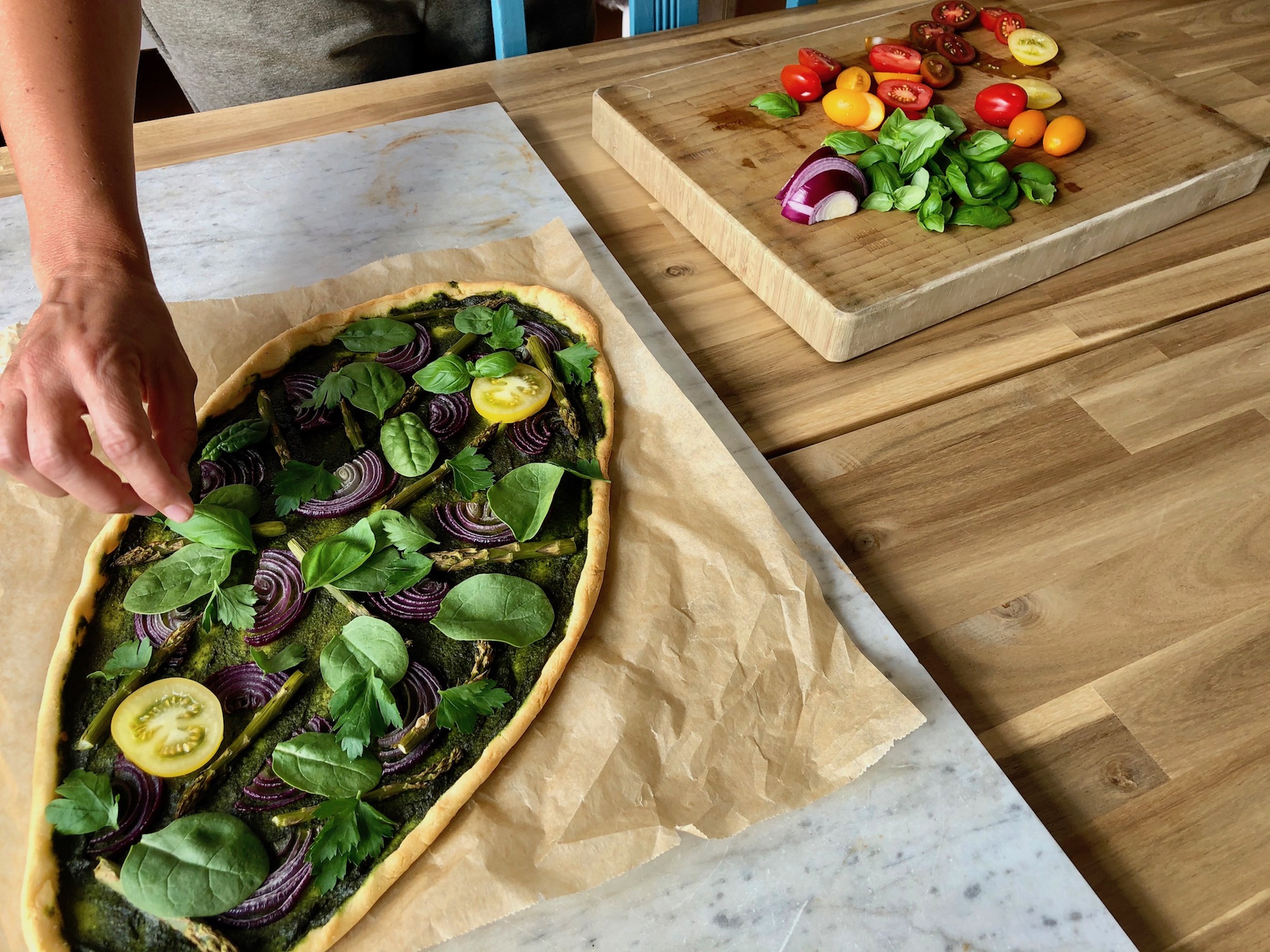 Toppar den gröna pizzan med babyspenat, örter och tomat